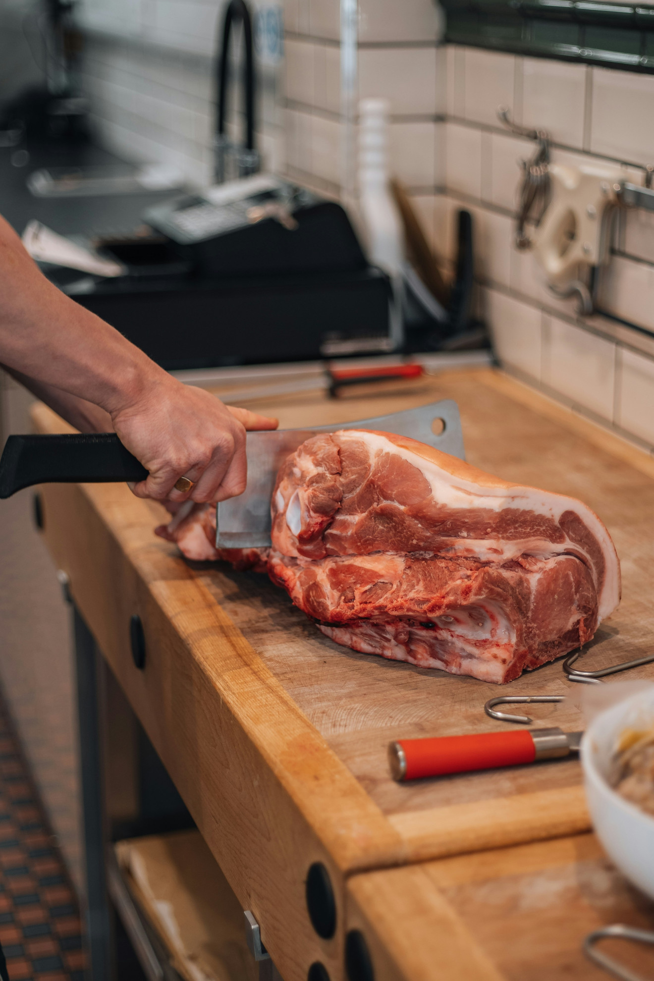 Metzger zerlegt ein Stück Schweinefleisch mit dem Fleischbeil.