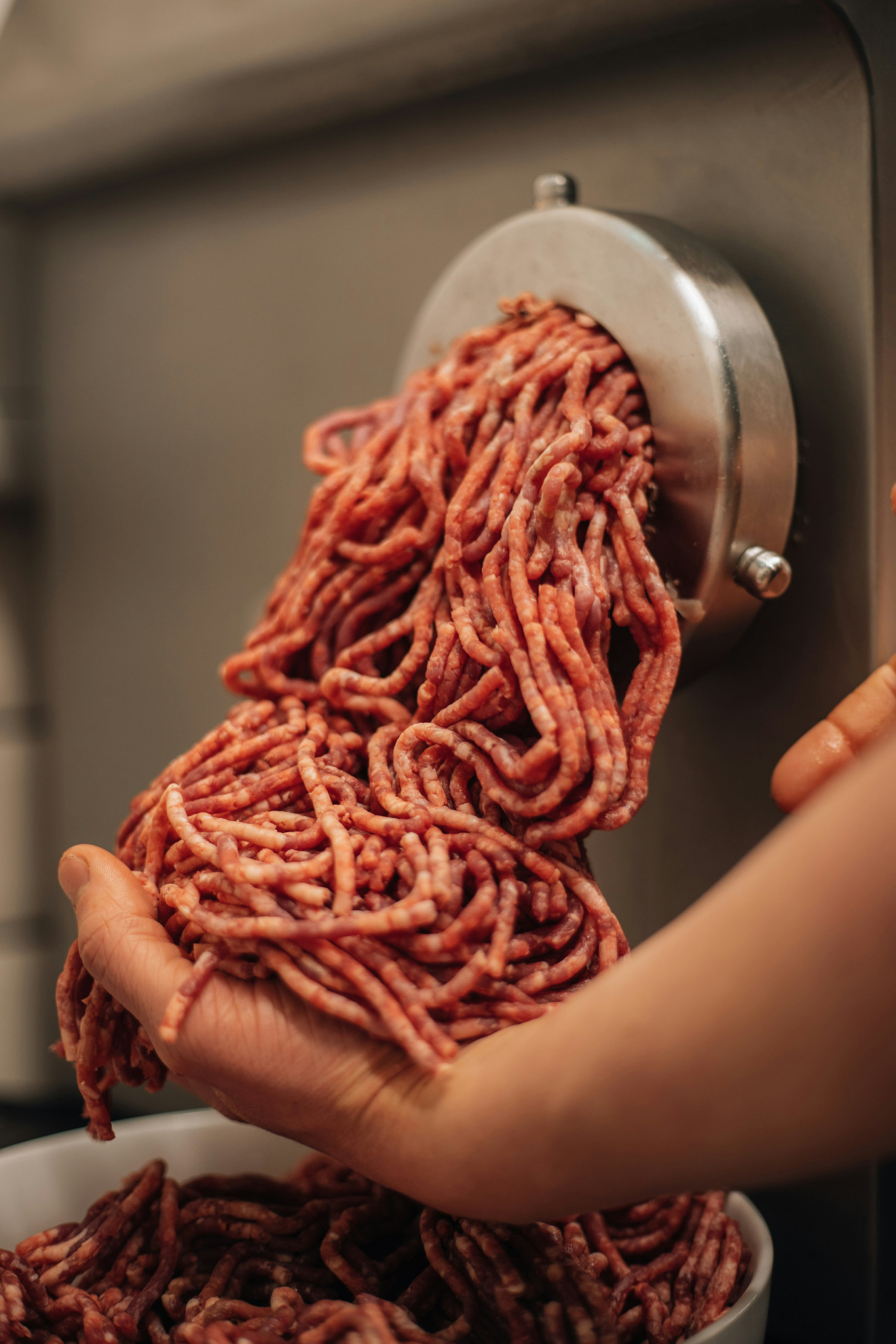 Frisch gewolftes Hackfleisch in der Hand eines Metzgers.