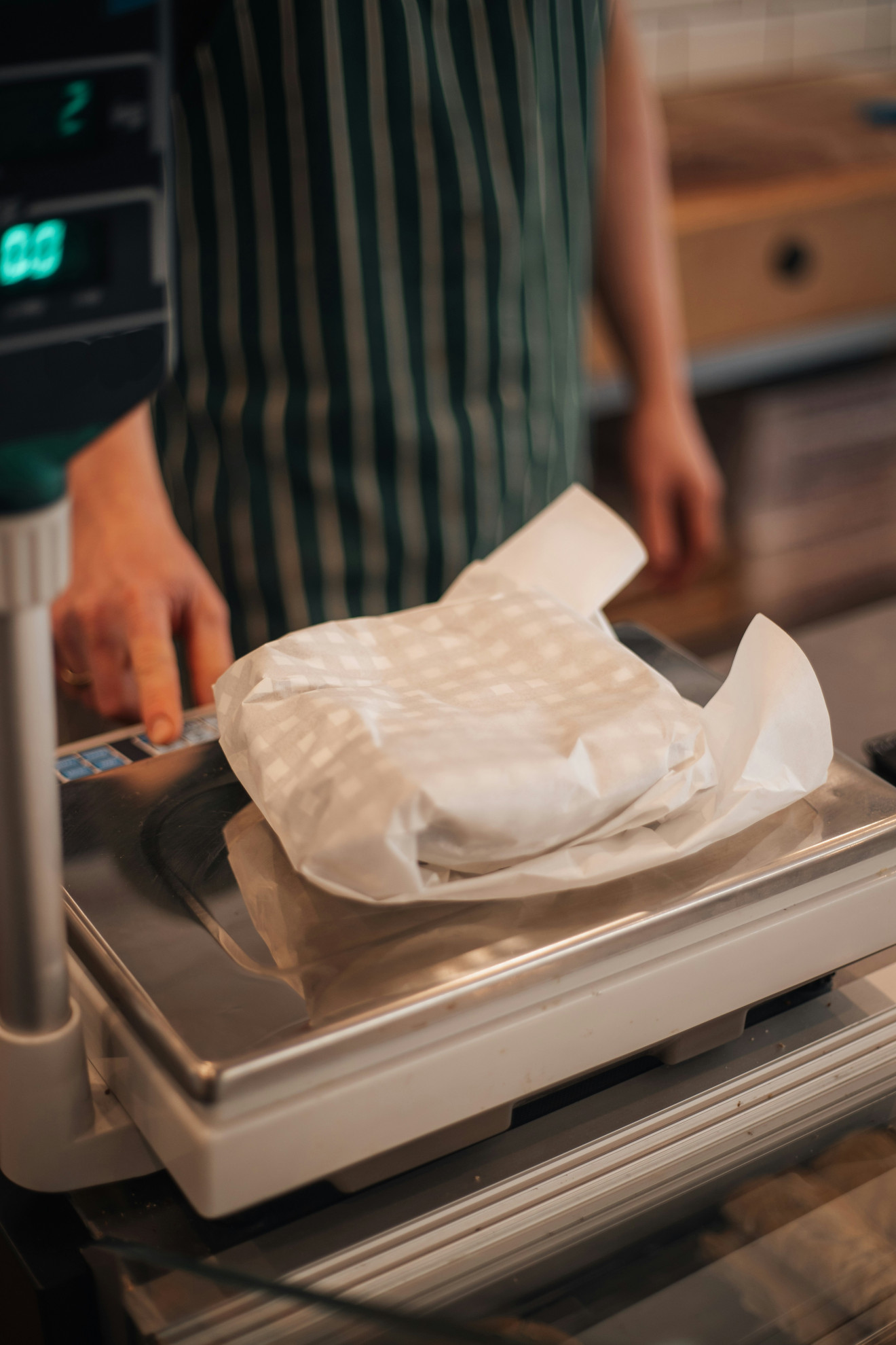 Verkäufer wiegt ein in Papier eingeschlagenes Fleischpaket auf der Ladenwaage.