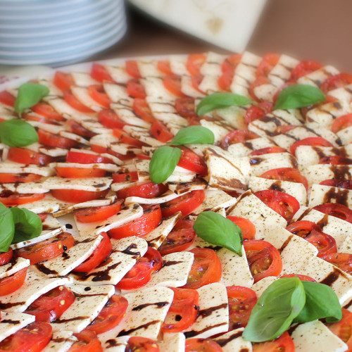 Caprese-Platte mit Mozzarella, Tomaten, Basilikum und Balsamico-Dressing.