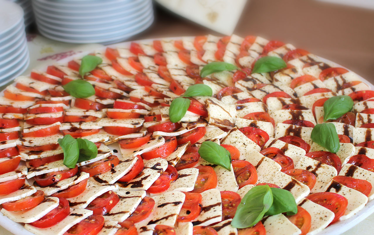 Caprese-Platte mit Mozzarella, Tomaten, Basilikum und Balsamico-Dressing.