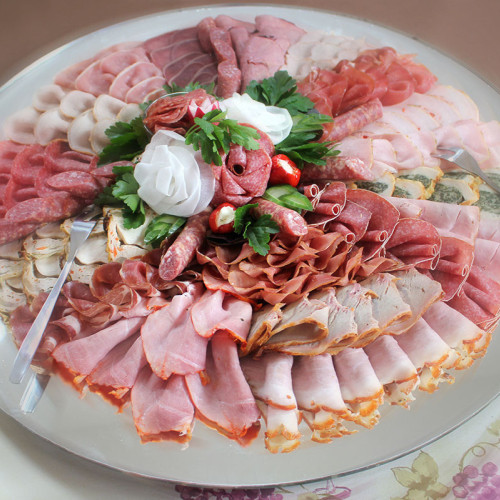 Aufschnittplatte mit Schinken- und Wurstsorten, dekoriert mit Rettich-Rosen und Petersilie.
